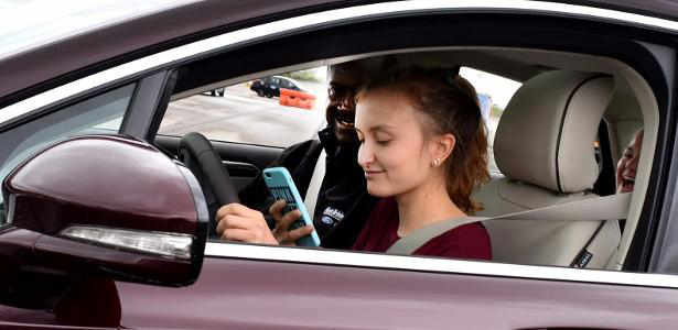 Foto de uma mulher usando o celular ao volante